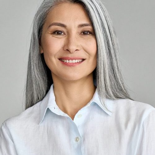 Vertical portrait of mature 50 years Asian business woman on grey background.